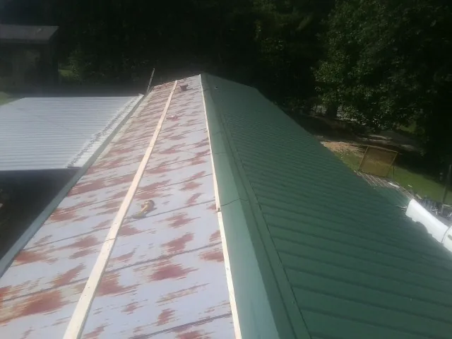 Old rusted panels beside newly installed green metal roofing — Wind Damage Roof Repair by Roofing Brothers in Modena