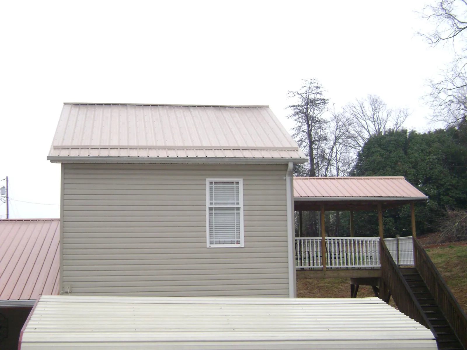 Tan metal roofs on a two story addition and attached porch, from a Roof Replacement job in Modena